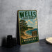 A vintage metal sign for Wells State Park, featuring a scenic landscape with pine trees, a lake, and a beach.