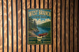 A vintage-style metal sign for West Branch State Park, featuring a scenic image of a lake and forest with a canoe, mounted on a wooden wall.
