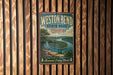 A vintage metal sign for "Weston Bend State Park, Missouri" hangs on a wooden wall, featuring a scenic landscape of a river and mountains.