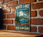 A vintage-style metal sign for White Lake State Park in New Hampshire, featuring a scenic landscape with a lake, mountains, and a sailboat.