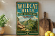 A vintage-style sign for Wildcat Hills, a state recreation area in Nebraska, featuring a scenic mountain landscape.