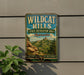 A vintage-style metal sign for Wildcat Hills, a state recreation area in Nebraska, featuring a scenic mountain landscape.