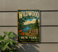A vintage-style metal sign for Wildwood State Park in New York, featuring a scenic landscape with a lake, mountains, and pine trees.
