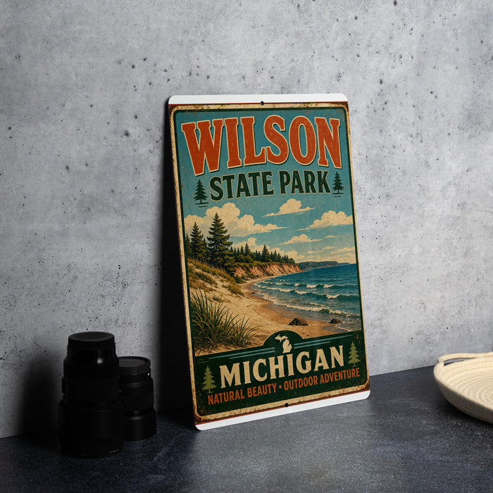 A vintage-style metal sign for Wilson State Park in Michigan, featuring a scenic landscape with a beach, mountains, and pine trees.