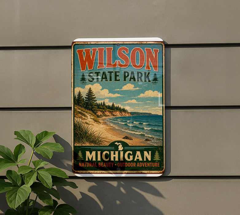A vintage-style metal sign for Wilson State Park in Michigan, featuring a scenic landscape with pine trees, a beach, and a lake.