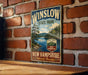 A vintage-style metal sign for Winslow State Park in New Hampshire, featuring a scenic landscape with pine trees, a lake, and mountains.