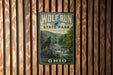 A vintage-style sign for Wolf Run State Park in Ohio, featuring a wolf silhouette and a scenic landscape.