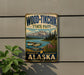 A vintage-style metal sign for Wood-Tikik State Park in Alaska, featuring a scenic landscape with mountains, a lake, and a plane.