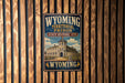 A vintage-style metal sign that reads "Wyoming Territorial Prison State Historic Site" is displayed on a wooden wall.