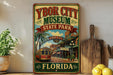 A vintage-style metal sign for Ybor City Museum, Florida, featuring a trolley car and a tropical city scene.