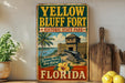 A vintage-style sign for Yellow Bluff Fort, a historic state park in Florida, featuring a palm tree, cannon, and a wooden fence.