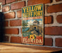 A vintage-style metal sign for the historic state park, Yellow Bluff Fort, in Florida, featuring a palm tree and a cannon.