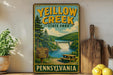 A vintage-style sign for Yellow Creek State Park in Pennsylvania, featuring a scenic image of the park with a waterfall and picnic area.