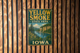 A vintage-style metal sign for Yellow Smoke State Park in Iowa, featuring a scenic landscape with a river and mountains.