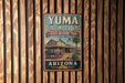 A vintage-style metal sign for Yuma Quartermaster Depot, a historic park in Arizona, with a wooden fence in the background.