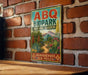 A vintage-style metal sign for the Abq Botanic Garden in Albuquerque, New Mexico, featuring a colorful illustration of desert plants and a mountain landscape.