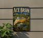 A vintage-style sign for the Ace Basin National Wildlife Refuge in South Carolina, featuring an illustration of a white egret and a crocodile in a tropical landscape.