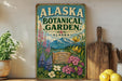 A vintage-style metal sign for the Alaska Botanical Garden, featuring illustrations of flowers, plants, and mountains.