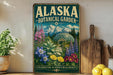 A vintage-style metal sign for the Alaska Botanical Garden, featuring a colorful illustration of a greenhouse surrounded by flowers and mountains.
