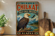 A vintage-style sign for the Bald Eagle Preserve in Alaska, featuring an eagle perched on a tree branch with mountains in the background.