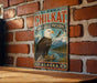 A vintage metal sign with an eagle perched on a rock, mounted on a brick wall.