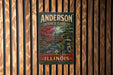 A vintage metal sign for Anderson Japanese Gardens in Illinois, featuring a scenic landscape with a bridge and trees.