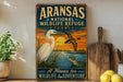A vintage-style metal sign for the Arkansas National Wildlife Refuge in Texas, featuring an illustration of a white egret and a duck flying over a body of water at sunset.
