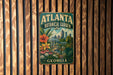 A vintage-style metal sign for the Atlanta Botanical Garden in Georgia, featuring a colorful illustration of the garden and the city skyline.