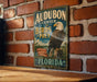 A vintage-style sign for Audubon Center for Birds of Prey in Florida, featuring an image of an eagle perched on a tree stump.