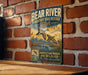 A vintage-style metal sign with a bird illustration and text, mounted on a brick wall.