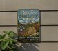 A vintage-style metal sign for Betty Ford Alpine Gardens in Colorado, featuring a scenic mountain landscape with flowers and plants.