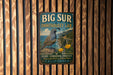 A vintage metal sign for the Big Sur Ornithology Lab, featuring a bird and a scenic landscape, mounted on a wooden wall.