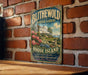 A vintage-style metal sign for Blitchewold Mansion Gardens in Rhode Island, featuring a large house surrounded by lush gardens and flowers.