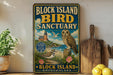 A vintage-style sign for the Block Island Bird Sanctuary in Rhode Island, featuring an illustration of a lighthouse, a bird, and a birdhouse.
