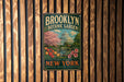 A vintage-style metal sign for the Brooklyn Botanic Garden, featuring a colorful illustration of the garden and a dome-shaped building.