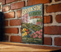 A vintage-style metal sign for "Brookside Gardens Maryland" is displayed on a brick wall, featuring a garden scene with flowers and a greenhouse.