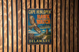 A vintage metal sign for Cape Henlopen Hawk Watch, featuring an illustration of a hawk in flight and text promoting the location.
