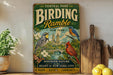 A vintage-style metal sign for Central Park's Birding Rumble, featuring illustrations of birds and nature, is displayed on a shelf next to a wooden cutting board and some lemons.