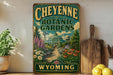 A vintage-style metal sign for Cheyenne Botanic Gardens in Wyoming, featuring a lush garden scene with a greenhouse and various plants.