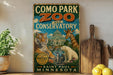 a vintage-style sign for Como Park Zoo and Conservatory, with illustrations of various animals such as a tiger, giraffe, and polar bear, along with a building and a pond. The sign is displayed on a shelf next to a wooden cutting board and some lemons.