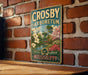 A vintage-style metal sign with the text "CROSBY ARBORETUM" and "MISSISSIPPI" is displayed on a brick wall.