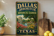 A vintage-style sign for the Dallas Arboretum and Botanical Garden in Texas, featuring a painting of a garden with a fountain and trees.