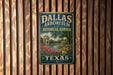 A vintage-style metal sign for the Dallas Arboretum and Botanical Garden in Texas, featuring a scenic landscape with a pond, trees, and flowers.