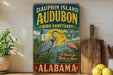 a vintage-style sign for Dauphin Island Audubon Bird Sanctuary in Alabama, with illustrations of birds and a lighthouse.