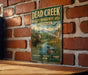 A vintage metal sign for Dead Creek Wildlife Management Area in Vermont, featuring a moose and a duck in a scenic landscape.