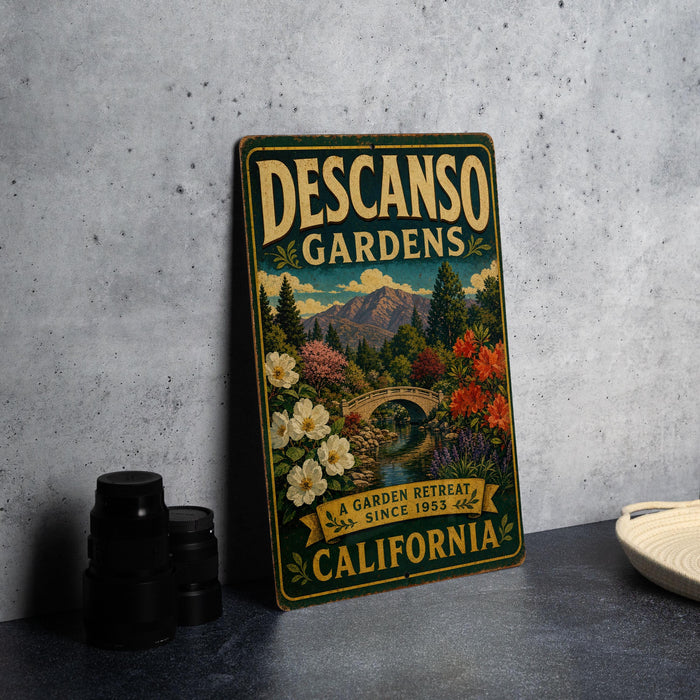 A vintage-style sign for Descanos Gardens, a garden retreat in California since 1953, featuring a scenic landscape with a bridge and flowers.