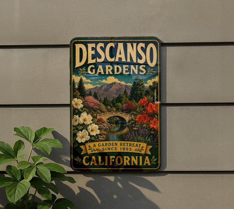 A vintage-style metal sign for Descanso Gardens, featuring a scenic landscape with mountains, flowers, and a bridge, is displayed on a wall.