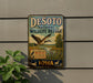 A vintage-style sign for the Desoto National Wildlife Refuge in Iowa, featuring a goose in flight and a sign that says "A Haven for Wildlife All to Enjoy".