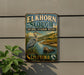 A vintage-style metal sign for the Elkhorn Slough National Estuarine Reserve in California, featuring an illustration of a heron and an otter in the water.