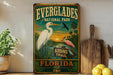 a vintage Everglades National Park sign with a bird illustration, placed on a wooden surface next to a wooden cutting board and some lemons.